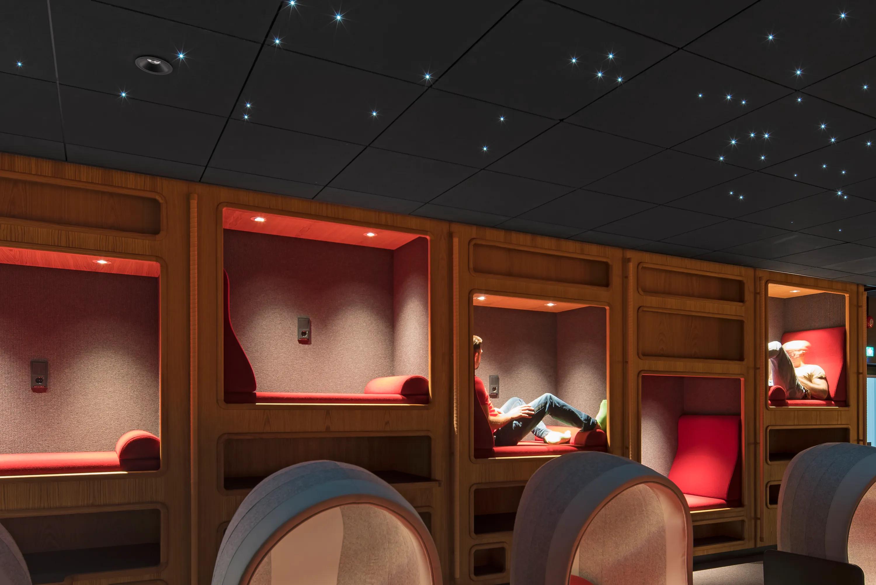A warm reading alcove area lined with timber pods, illuminated by a dark acoustic ceiling sprinkled with star-like integrated LED points
