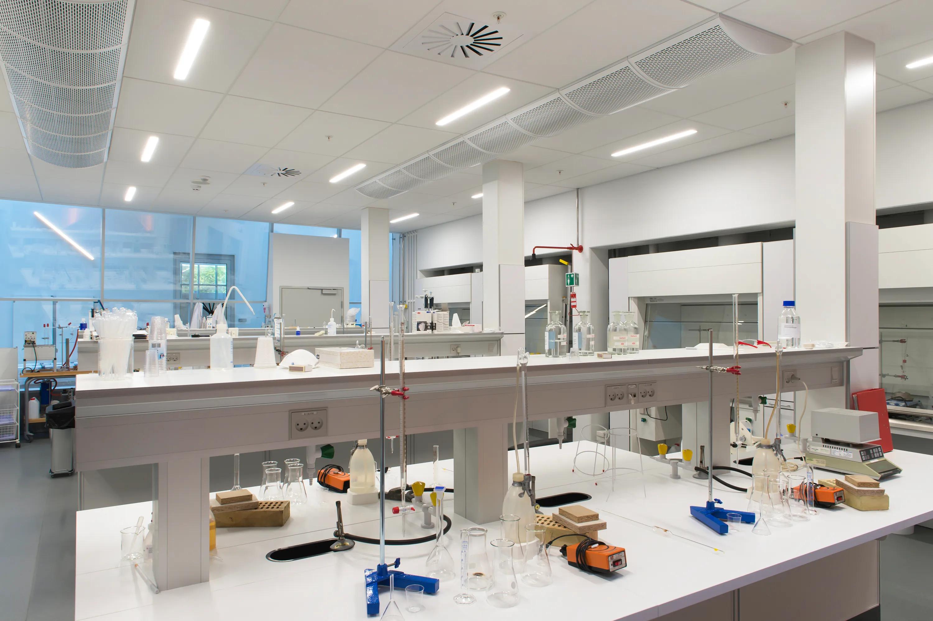 Laboratory with white acoustic ceiling tiles, workbenches equipped with glassware and instruments, and a clean, organised layout with integrated ventilation systems.