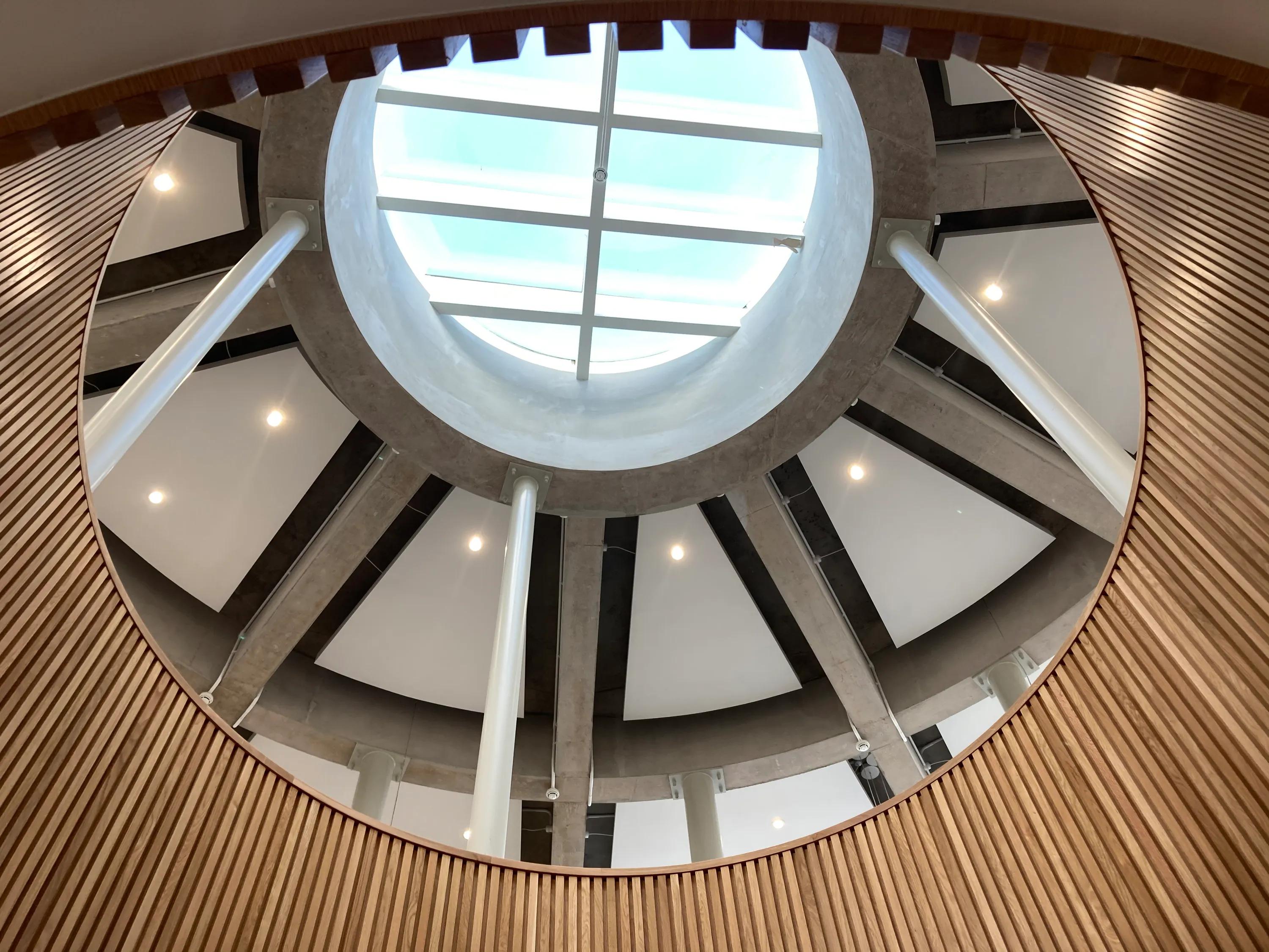 A circular skylight viewed from below, showing triangular acoustic panels integrated between radial concrete beams.
