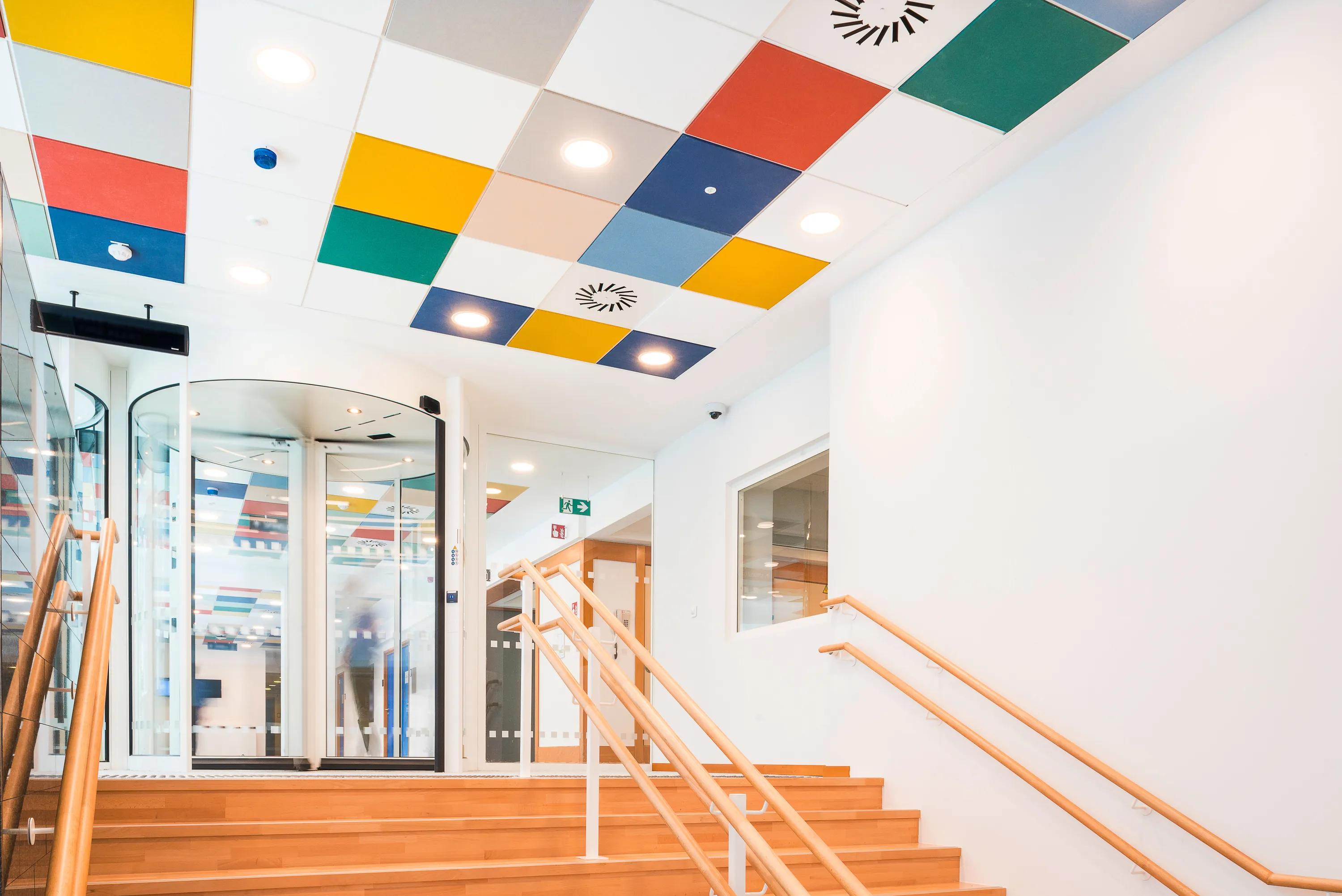 A checkered tile ceiling with colourful Rockfon Color-all ceiling tiles