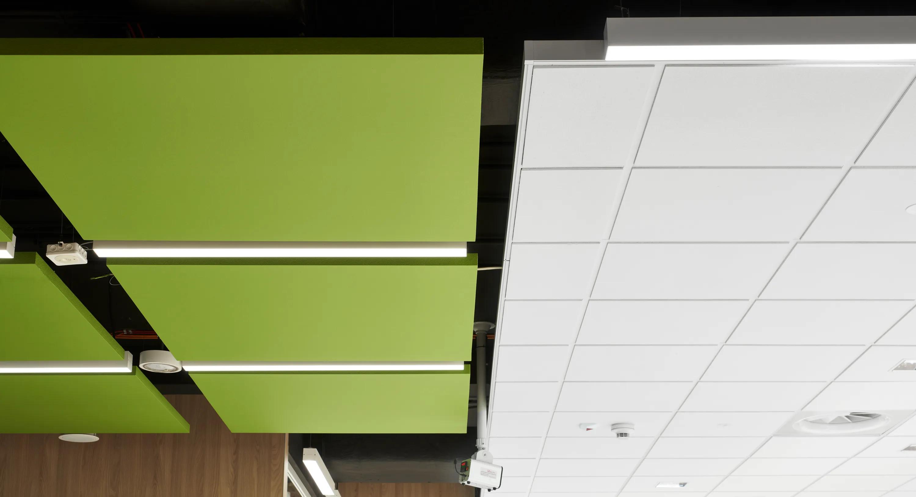 A close-up view of green rectangular acoustic ceiling islands suspended beside a white acoustic ceiling grid.